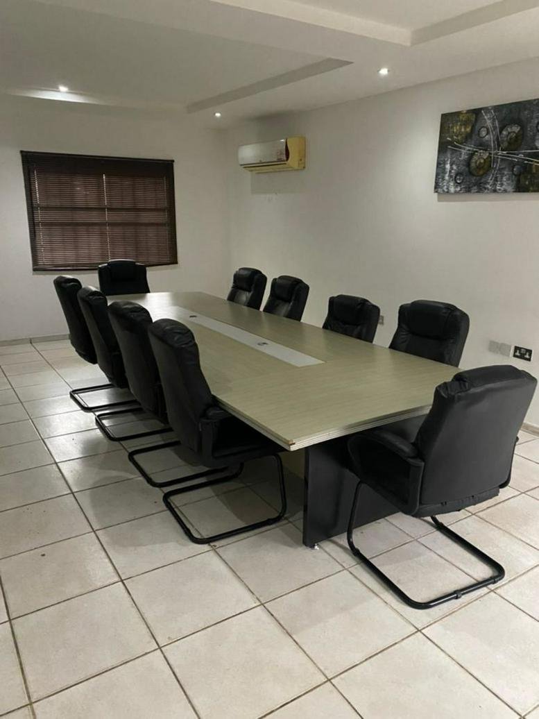 Spacious boardroom featuring a long light-wood conference table and several black executive chairs.