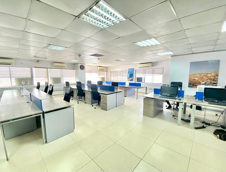 Large open-plan office space with multiple rows of workstations and blue privacy dividers.