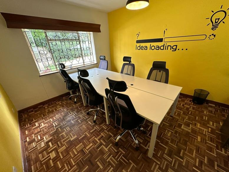 Bright coworking office at 29 Westlands Avenue featuring a yellow feature wall and white shared desks.