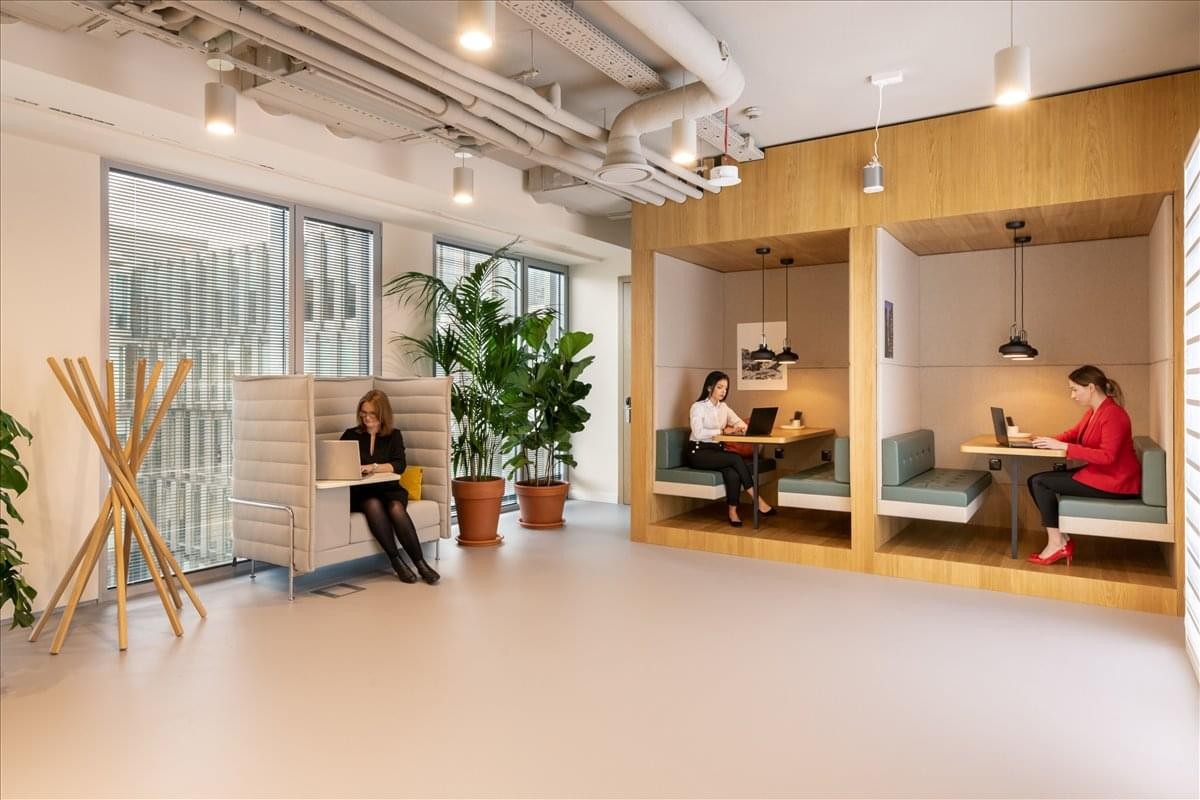 Spacious communal lounge at Marriott Workspace, 3026 Route Principale featuring private work booths and indoor plants.
