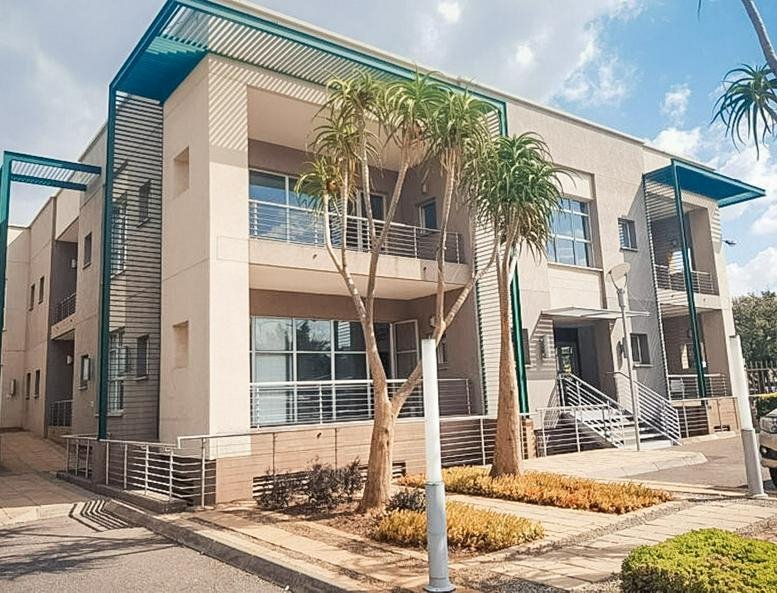 Modern multi-story office building featuring tan brick and blue architectural overhangs.