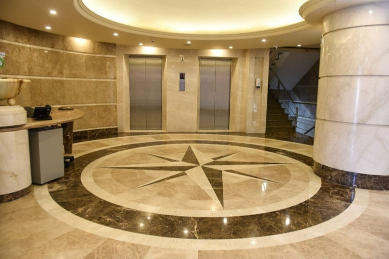 Polished marble lobby with two elevators and a compass rose floor inlay.