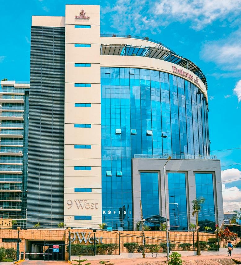Full exterior view of the 9 West Building showing its rounded glass architecture and landscaped entrance.