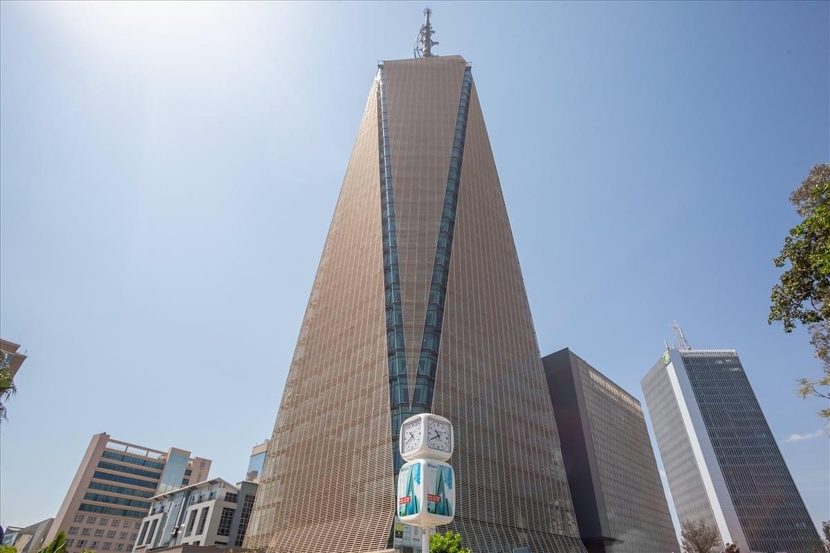 The soaring, triangular glass and stone exterior of Britam Towers against a clear blue sky.