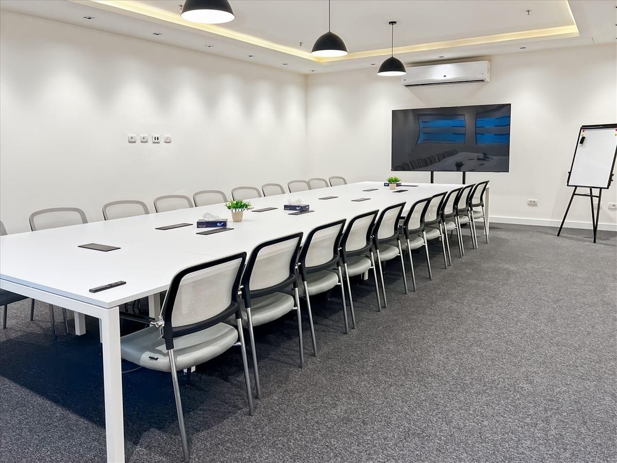 Spacious boardroom at Business Hub, Cairo International Airport with a long white table and video conferencing screen.