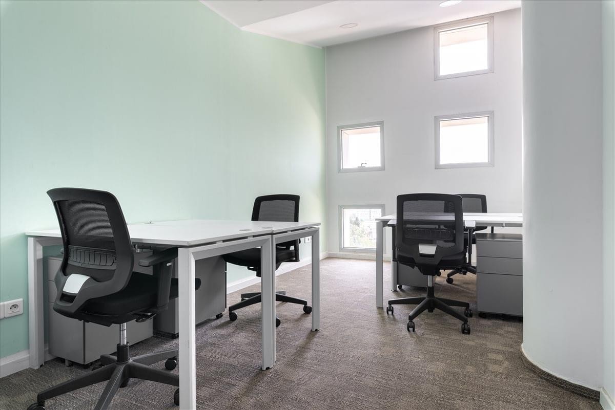 Spacious interior at Casa Shore 1 with white desks, ergonomic chairs, and high ceilings with upper-level windows.