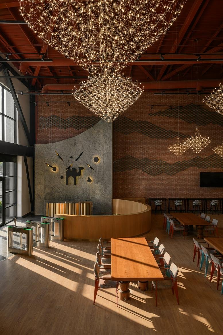 Grand reception lobby with a stone feature wall, turnstile access, and massive wire-mesh chandeliers.
