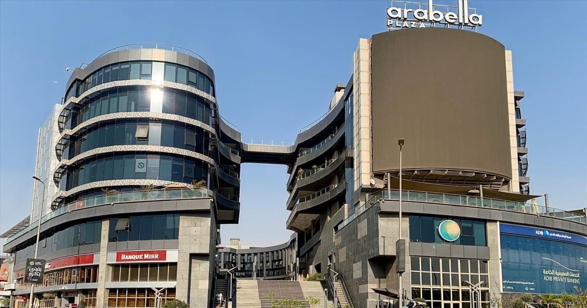 Wide exterior view of the curved glass office building at Arabella Plaza under a clear sky.