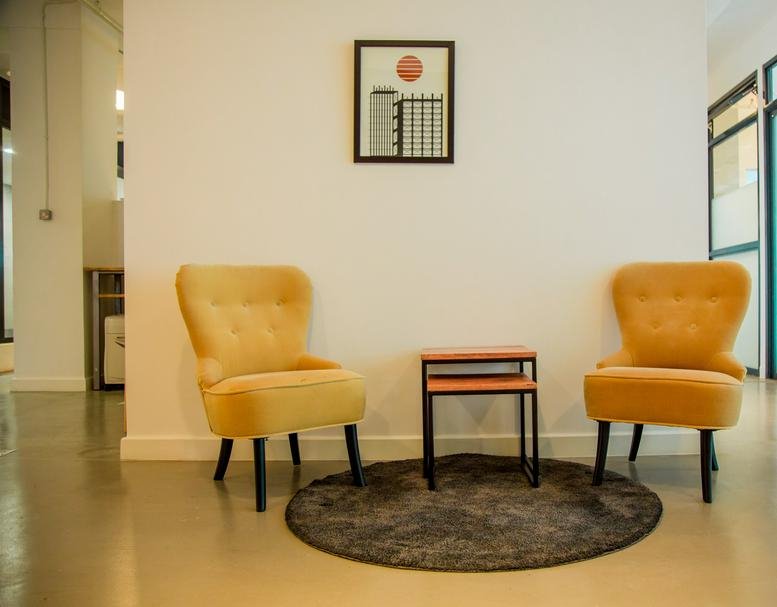 Lounge area at The Promenade with two yellow armchairs, a small nested table, and a circular rug.