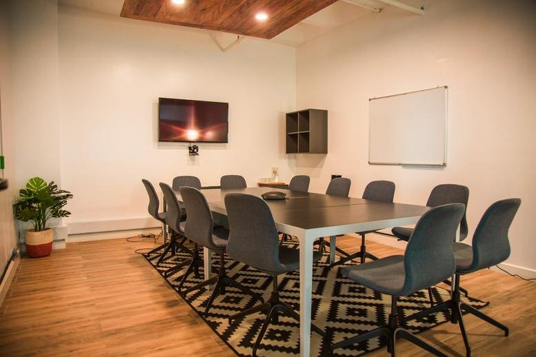 Professional meeting room at The Promenade with a long conference table and wall-mounted screen.