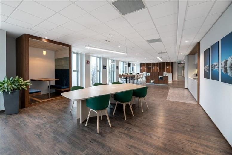 Large communal coworking space with wood-style flooring and a variety of seating areas.
