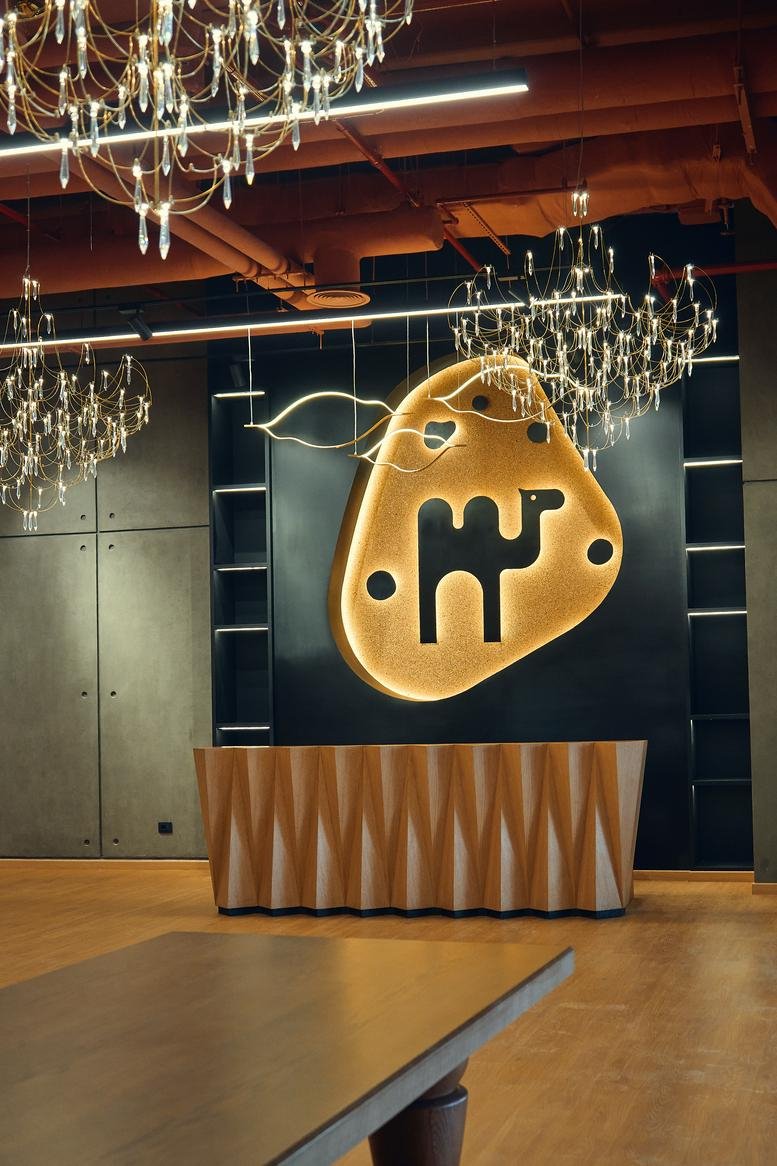 Reception area at Majarrah, 26th of July Corridor featuring a wooden desk and a back-lit camel logo.