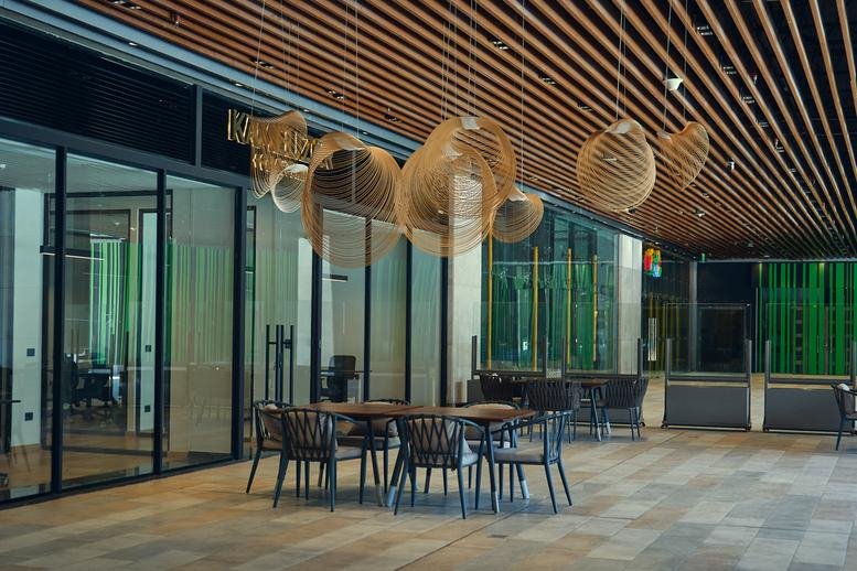 Communal lounge with stylish slatted wood ceiling, unique pendant lights, and modern dining furniture.
