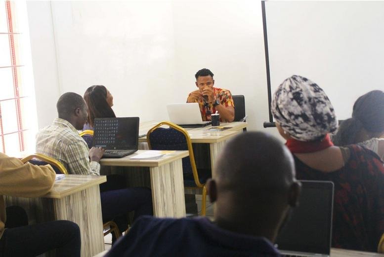 A seminar at No. 16, Emeka Anyaoku Street, Area 11 with students using laptops and a teacher.