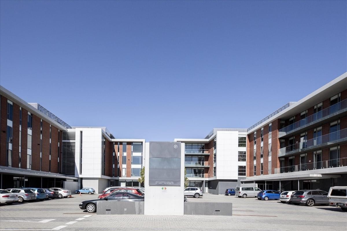 Exterior courtyard of 1 Bridgeway showing the modern red brick and white facade under a clear blue sky.