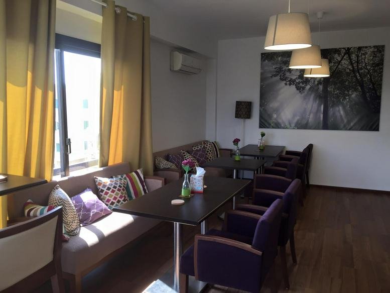Spacious communal lounge at 158 Hegaz St, Floor 5, Heliopolis with purple armchairs, a sofa, and natural light.