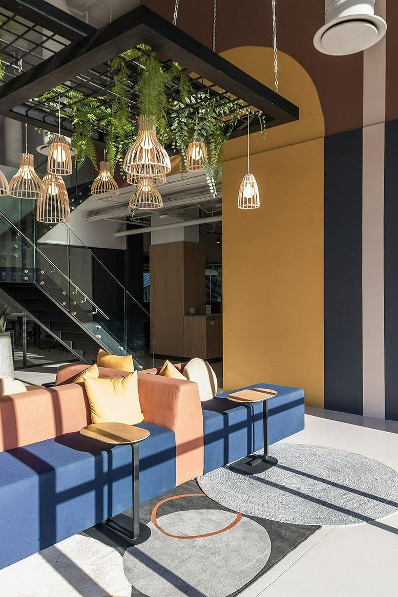 Colorful communal lounge at Cape Quarter featuring blue and terracotta seating and hanging plants.