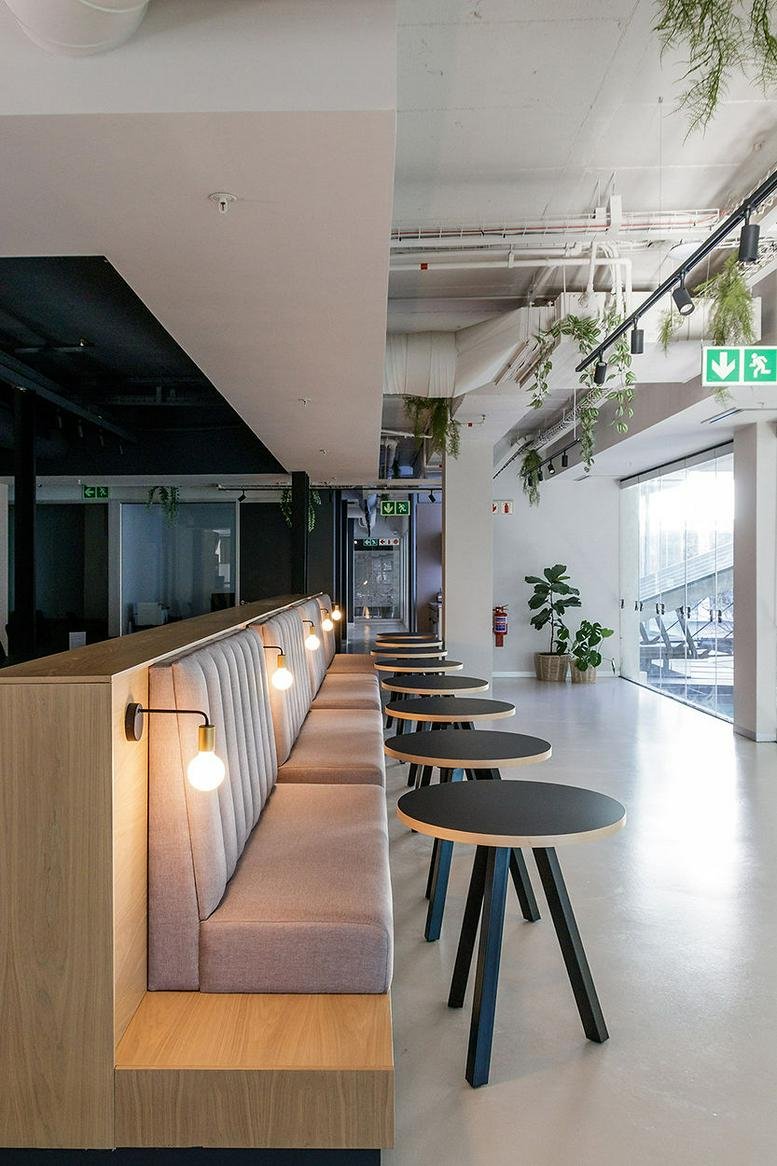 Wide-angle interior of Cape Quarter office with plush seating and industrial ceilings.