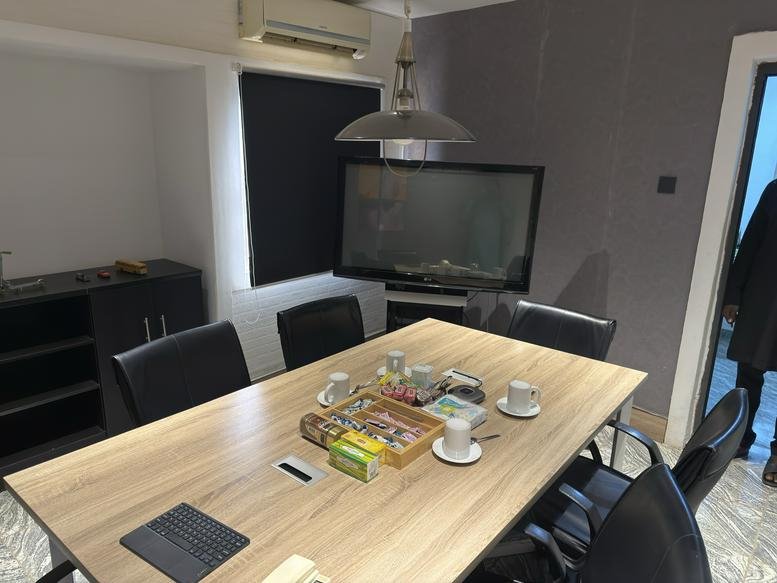 Six-person conference table set with tea cups and a large screen monitor.