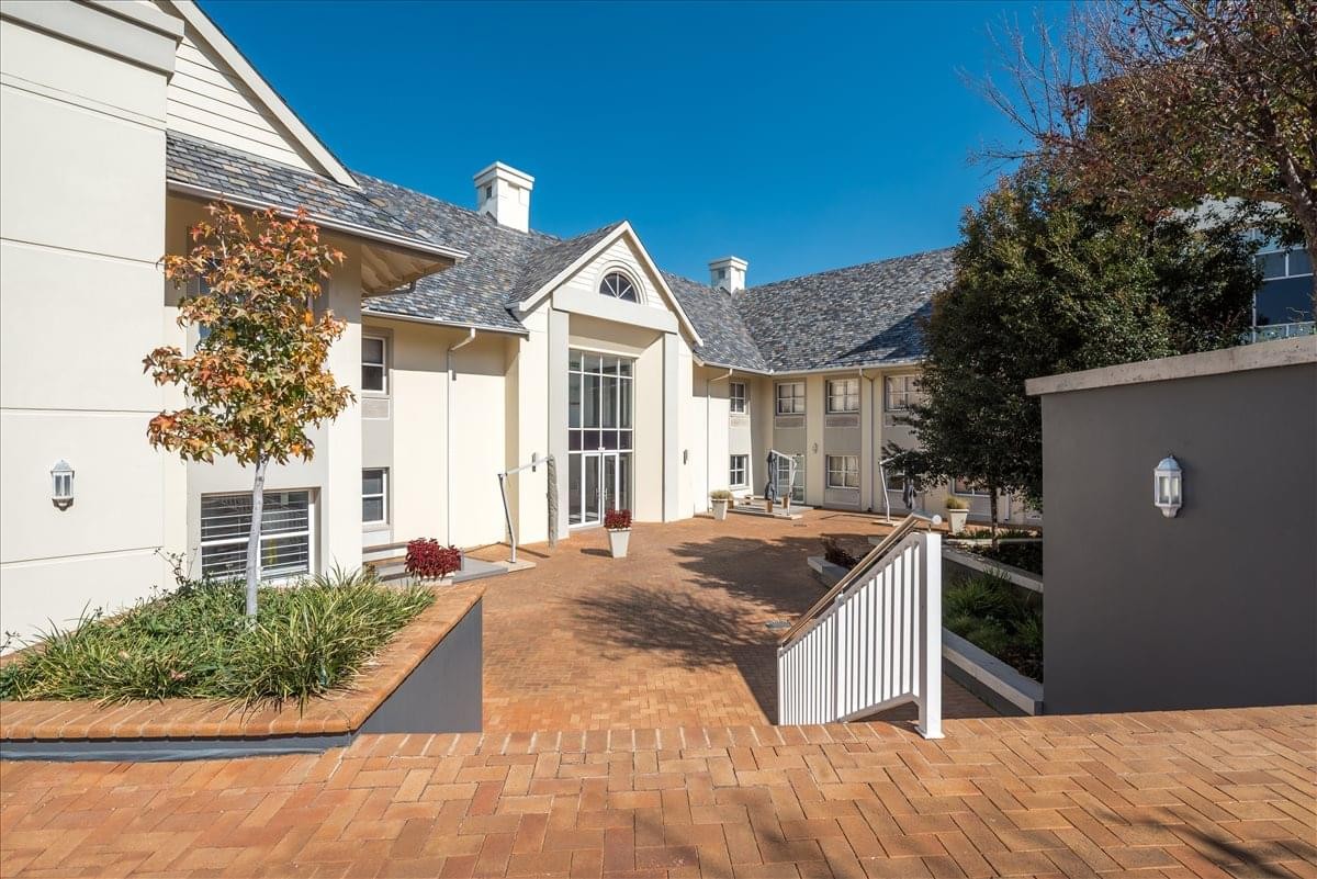 Exterior view of the multi-story Cedarwood House, Ground Floor, 33 Ballyclare Drive building with paved courtyard.