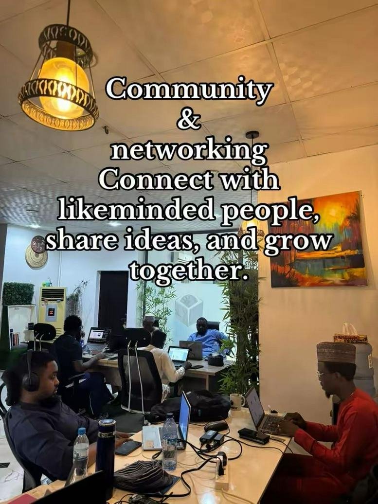 Spacious coworking area at OfficeBox with warm lighting, colorful artwork, and people working at a long communal table.