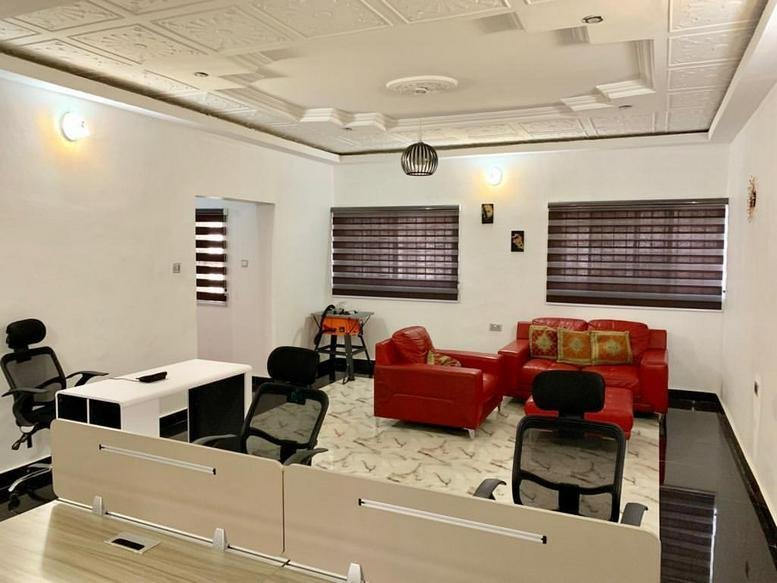 Spacious open-plan workspace at 4a Volta Street, Maitama, Abuja, Nigeria featuring red leather sofas and white desks.