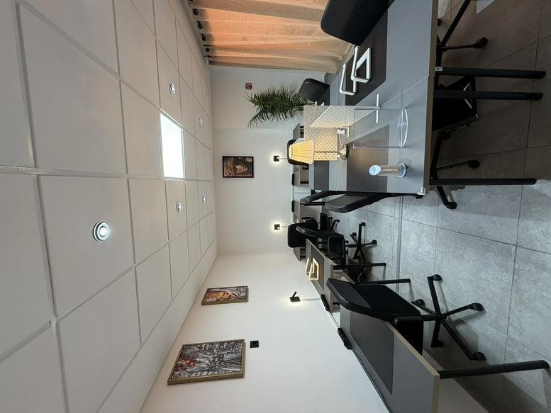 Open-plan office area with rows of modern workstations and ergonomic black chairs.