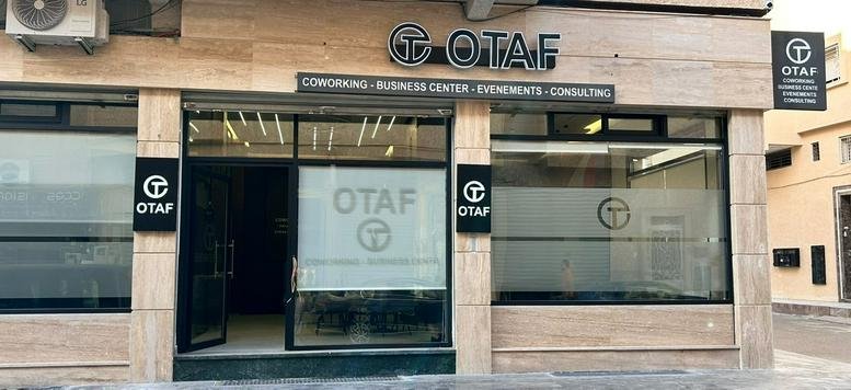 Exterior view of the OTAF Coworking center entrance with glass windows and prominent branding.