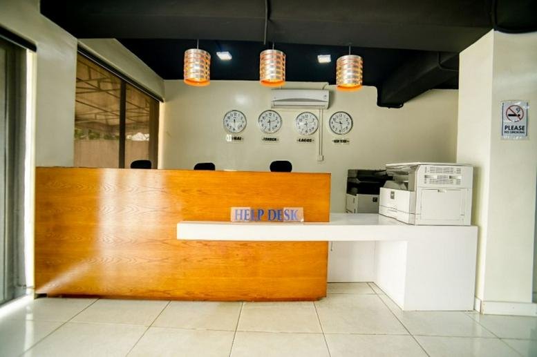 Bright reception desk at 54 Adeniyi Jones Avenue featuring wood paneling, world clocks, and modern pendant lights.