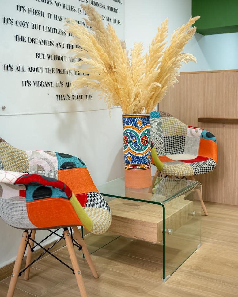 Bright reception area at The Work Loft featuring patchwork armchairs and a decorative vase.