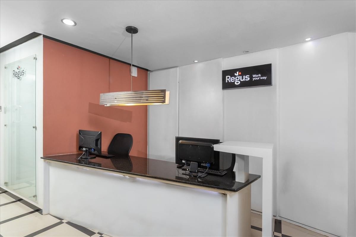Bright reception area at AHA Towers featuring a white desk, burnt orange wall, and glass partitions.