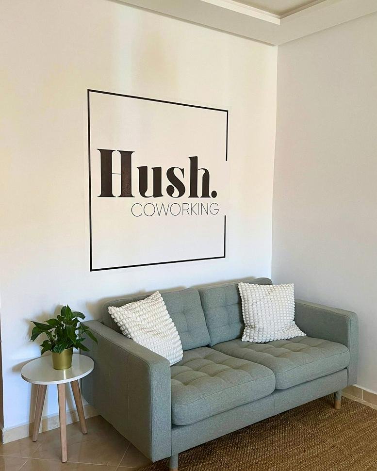 Reception area at Al Baraka Residence, Al-Wiqaya featuring a sage green sofa and branded wall art.