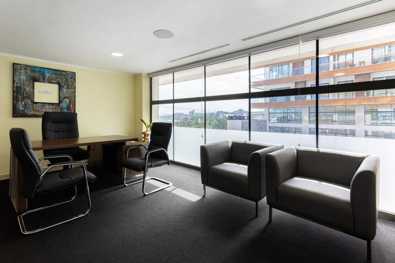 Private office suite with a dark wood desk, black leather chairs, and floor-to-ceiling windows.
