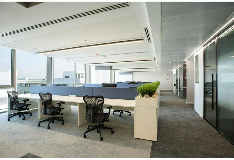 Spacious open-plan workspace at Building 7, 5A Waterway, Ring Road, New Cairo, Egypt with ergonomic chairs and plants.