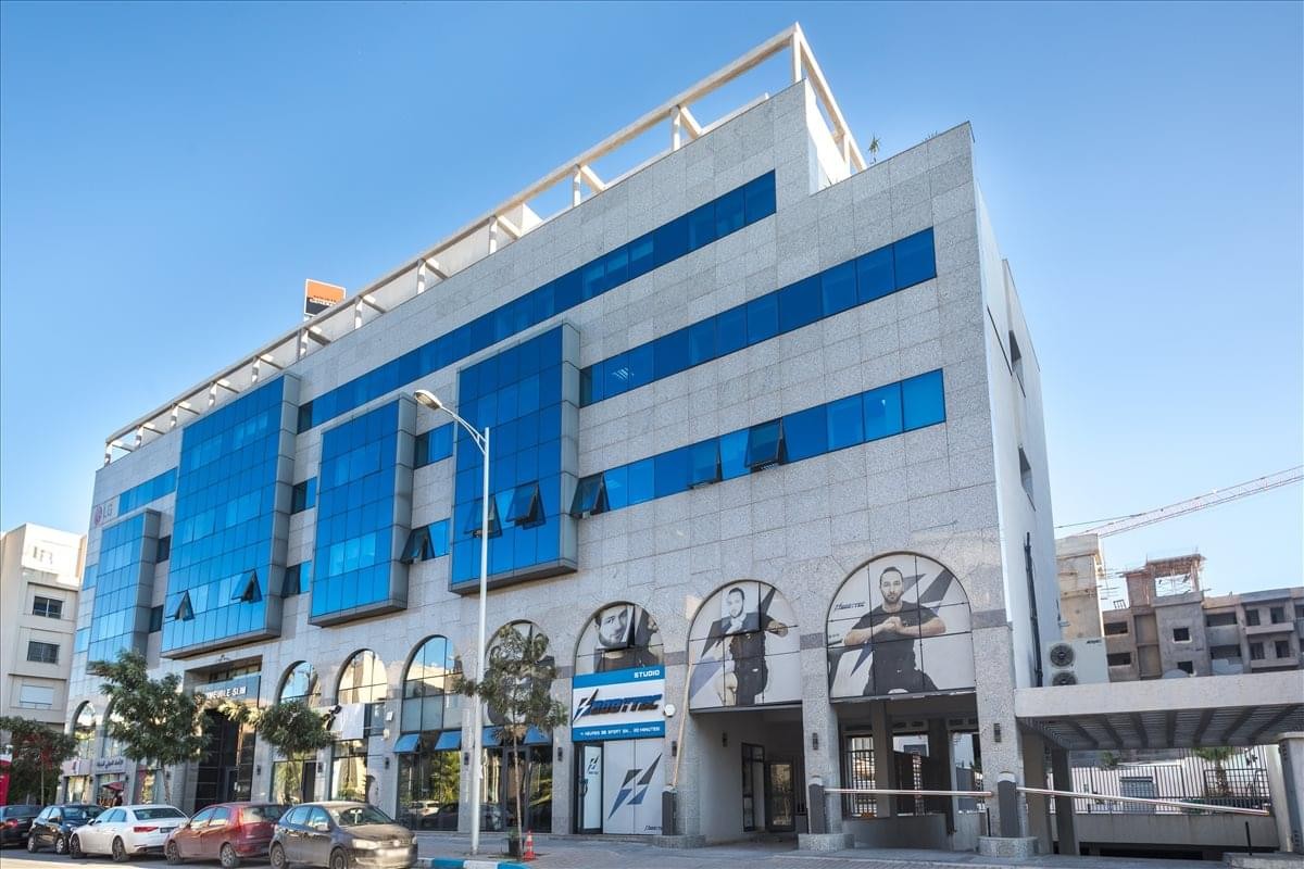 Exterior view of the modern stone and blue glass facade of Building SLIM.