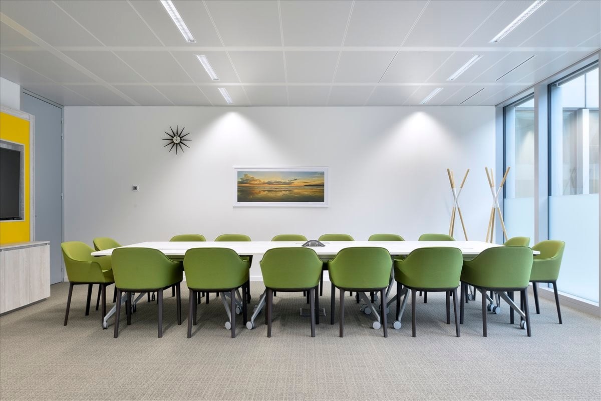 Spacious meeting room at Cementers Plaza with a long white table and vibrant green chairs.