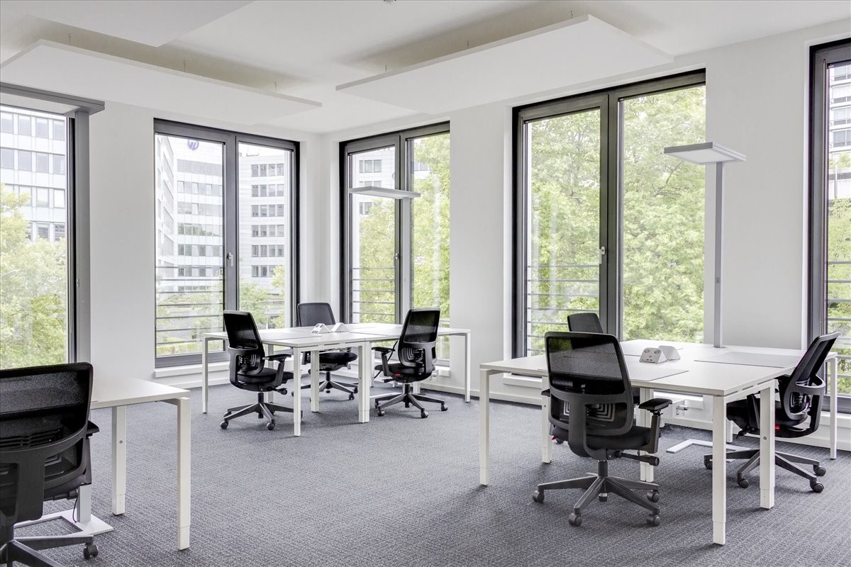 Spacious open-plan workspace at El Shams Sporting Club with white desks and large windows.