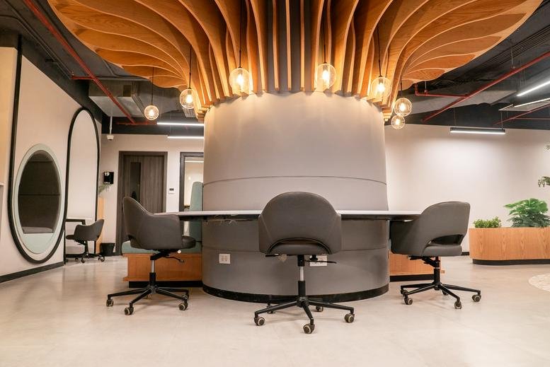 Modern coworking hub at Enawalks Plaza with a sculptural wood ceiling feature and grey round desk.