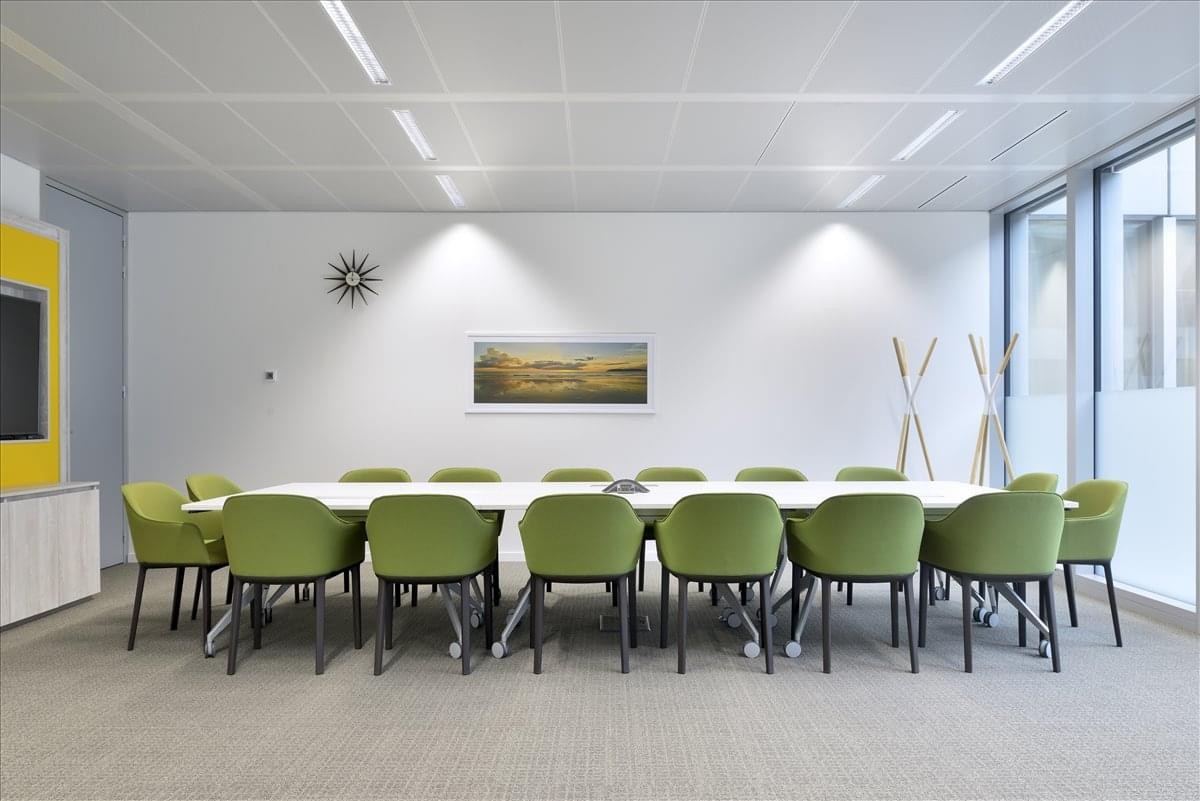 Spacious boardroom at Exhibitions Ground, Cairo–Alexandria Desert Road with green chairs and a long white table.