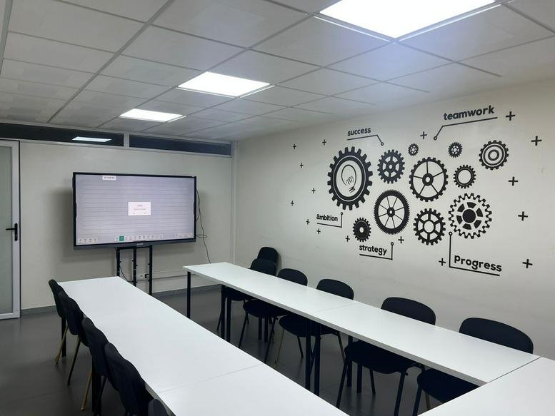 Spacious boardroom at Galeries Mamounia, Block C, Office 44 with long white tables and gear wall decals.