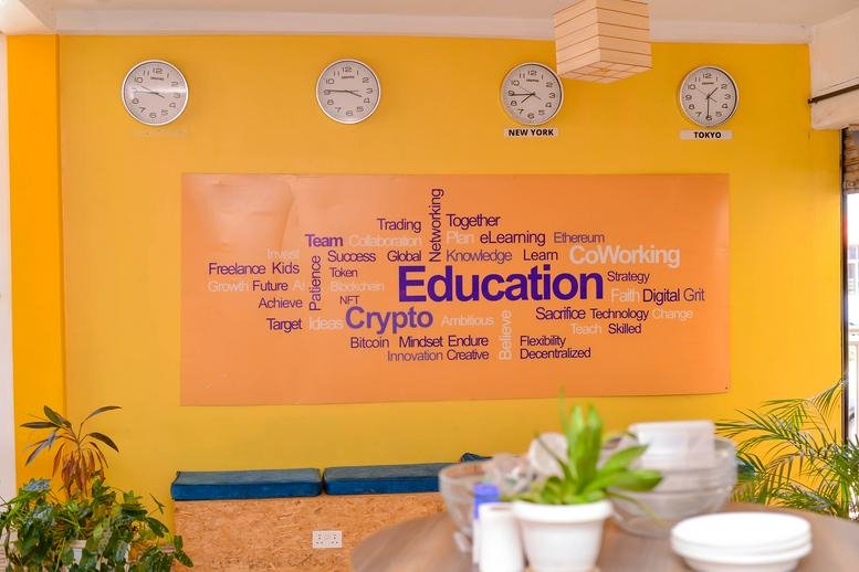 Reception area at Cooper House 2 with a bright yellow wall, world clocks, and an education-themed word cloud mural.