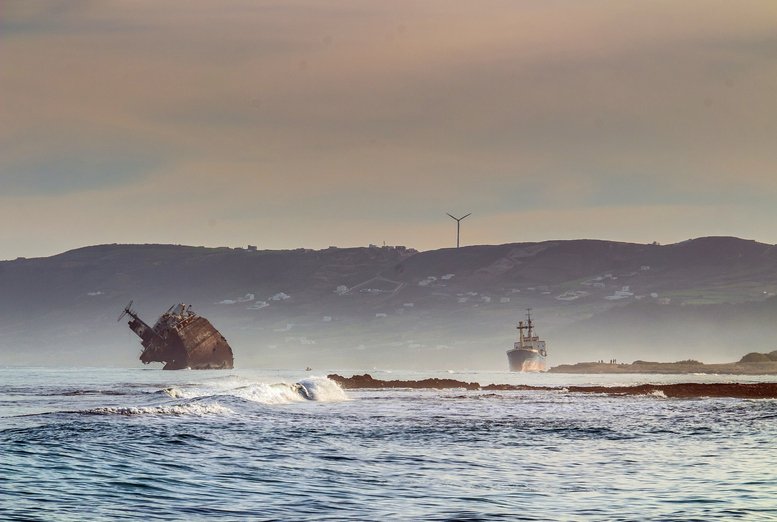 Distant view of a shipwreck and a ship near the coast at Harbor Drive, Medina, Bizerte, Tunisia.