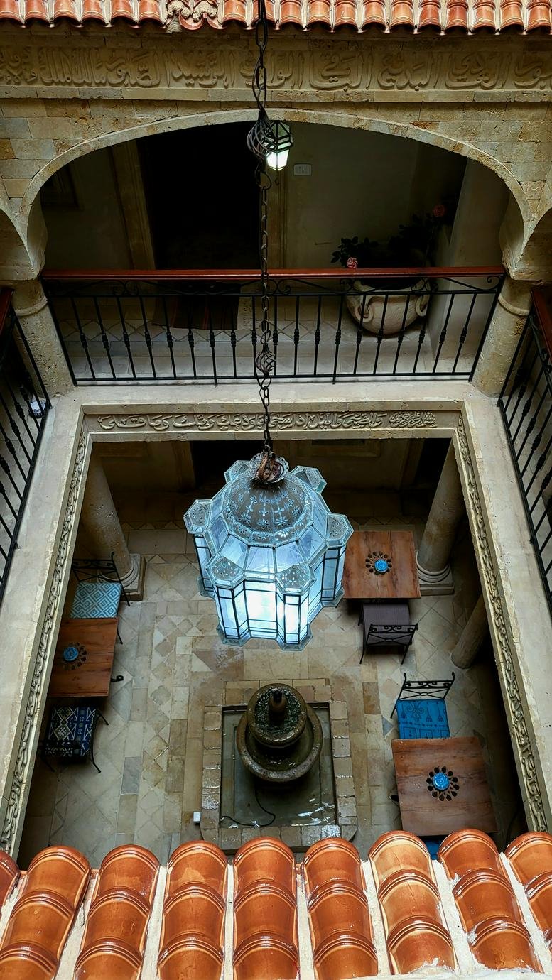 High-angle view of a traditional courtyard with a central fountain and hanging glass lantern.