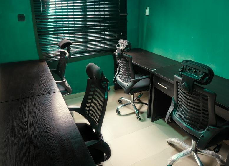 Private office with large desk and ergonomic chairs.