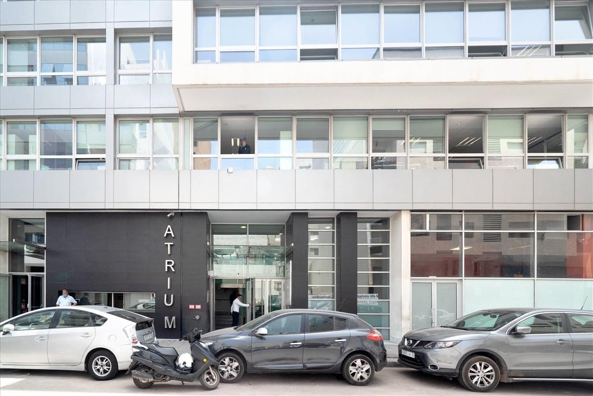 Exterior street view of the Immeuble ATRIUM building entrance with parked cars.