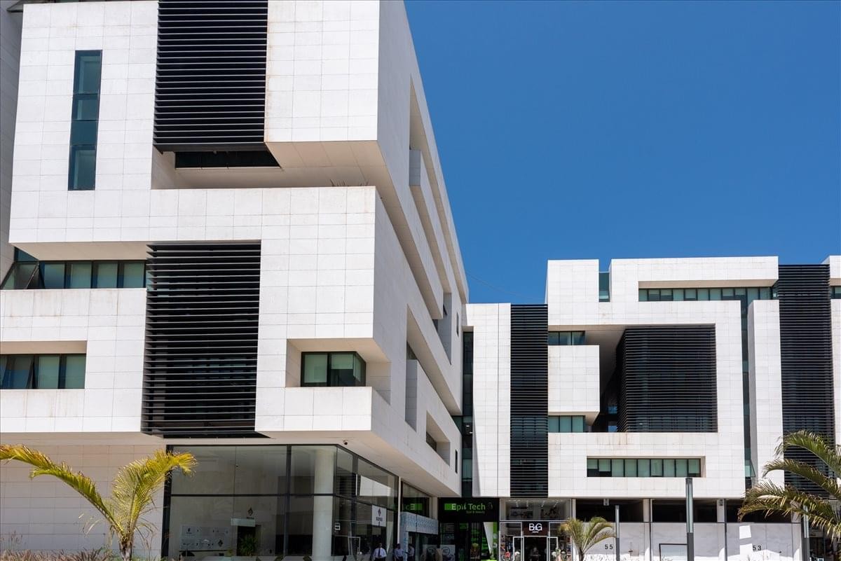 Modern white geometric facade of the Immeuble Mahaj Ryad Center under a clear blue sky.
