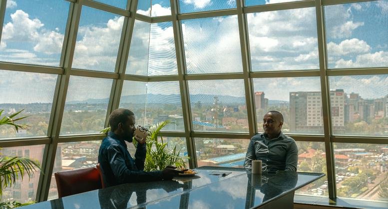 Sunny communal lounge with floor-to-ceiling windows and city views.
