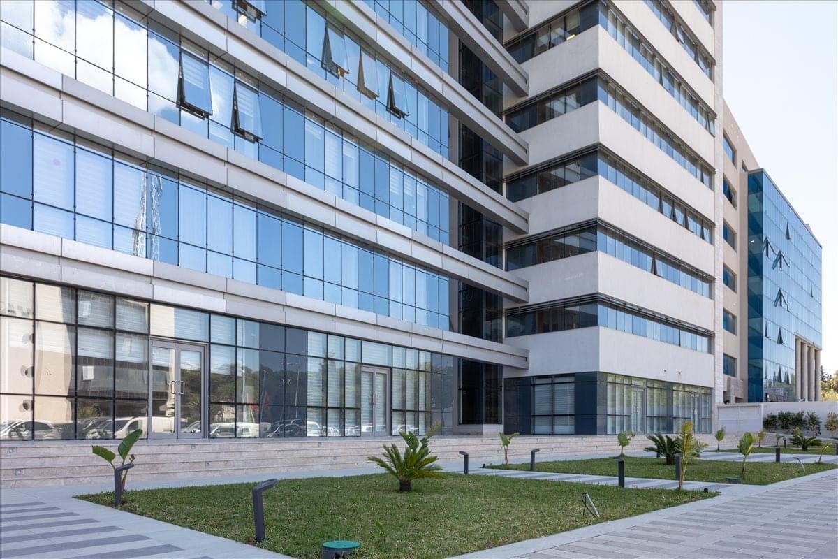 Exterior of the glass-facade building at Lot B17, Centre Urbain Nord, Tunis with manicured lawn.