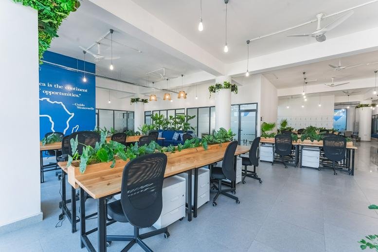 Spacious interior of Westerwelle Startup Haus, Mombasa Island featuring wooden desks and lush greenery.