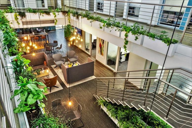Multilevel atrium at Nicol Main Office Park with hanging plants and diverse seating areas.